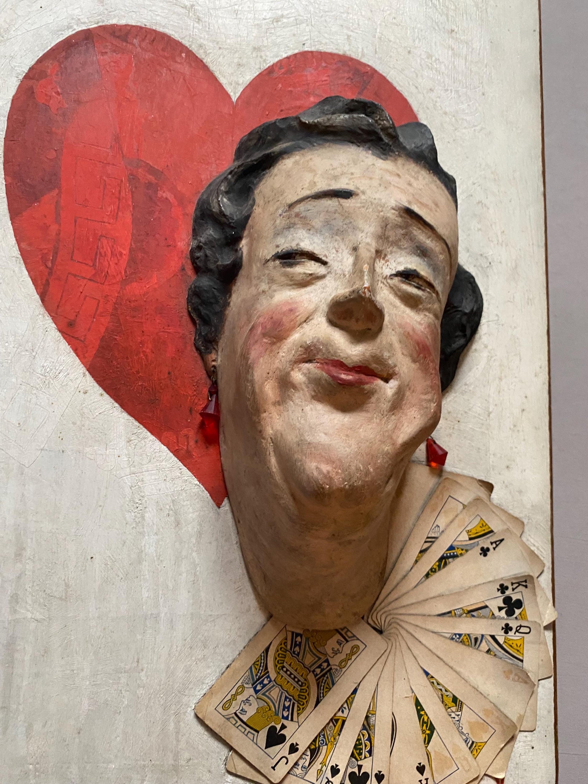 The Queen of Hearts. A Plaster Head Affixed To Decorated Board With Decorative Playing Cards and Glass Earrings. 1930s. Size: 38 x 58.5 cms.