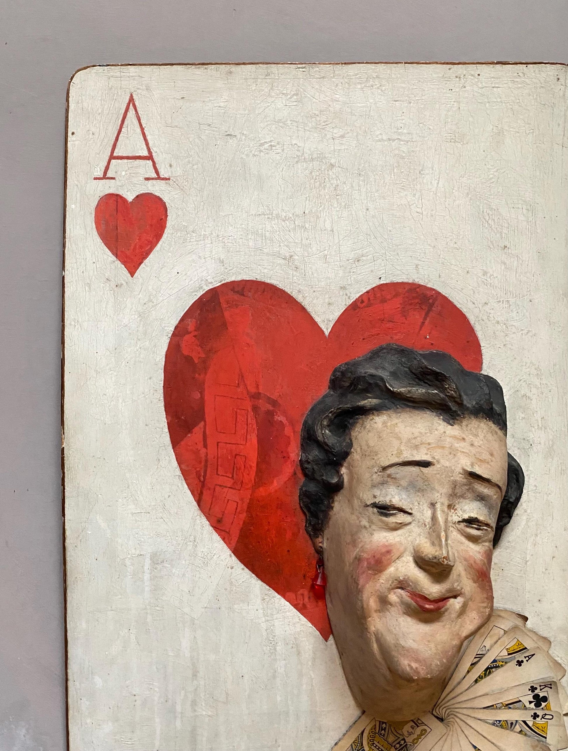 The Queen of Hearts. A Plaster Head Affixed To Decorated Board With Decorative Playing Cards and Glass Earrings. 1930s. Size: 38 x 58.5 cms.