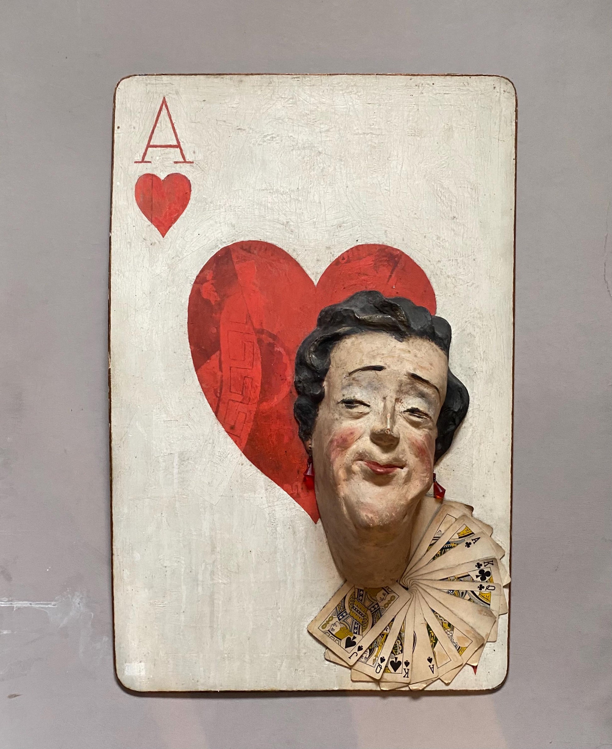 The Queen of Hearts. A Plaster Head Affixed To Decorated Board With Decorative Playing Cards and Glass Earrings. 1930s. Size: 38 x 58.5 cms.