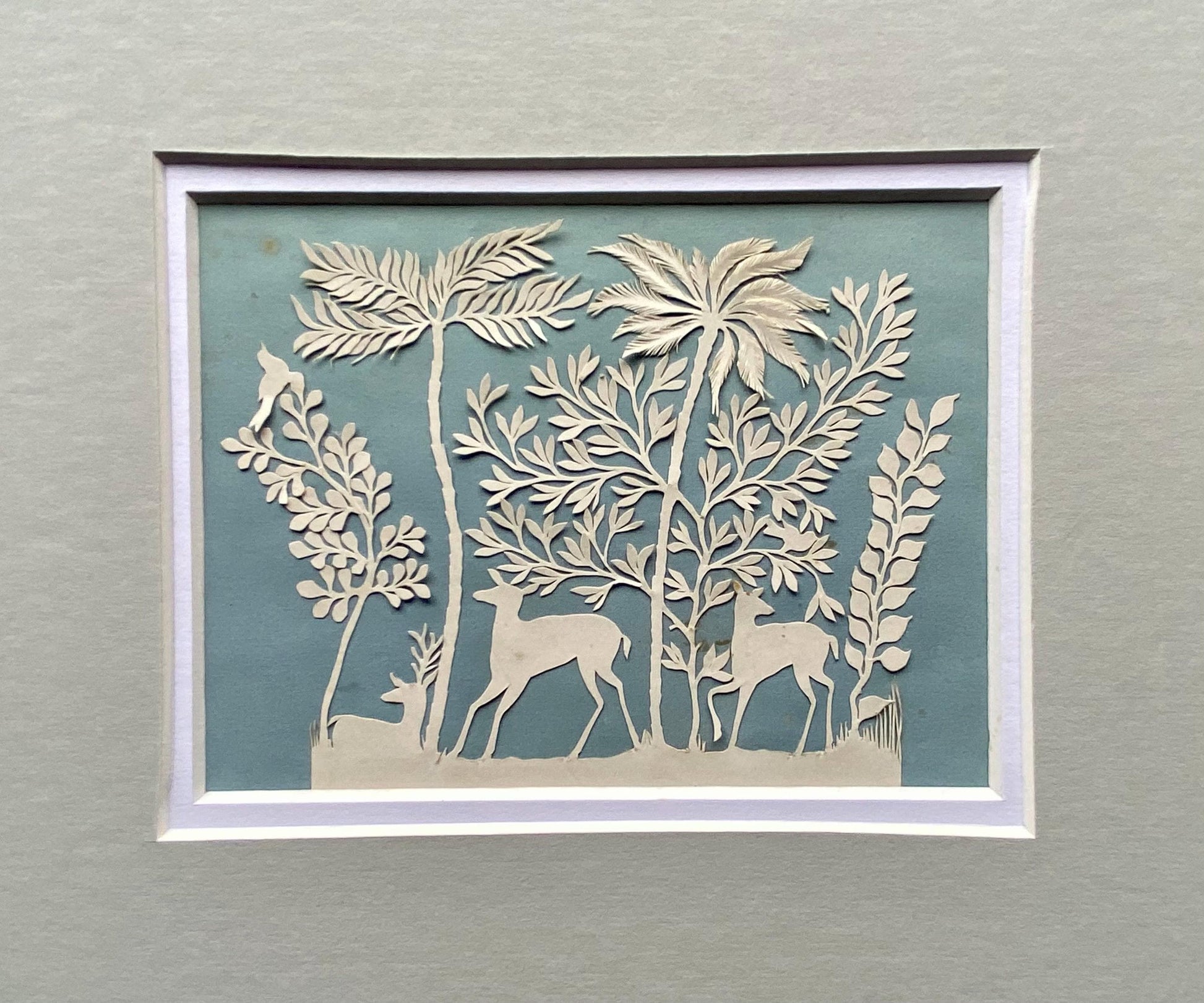 An Antique Paper Cut. Deer In a Wood. White on a Pale Blue Ground. Late Georgian, Early Victorian. Size: 9 x 12.5 cms.