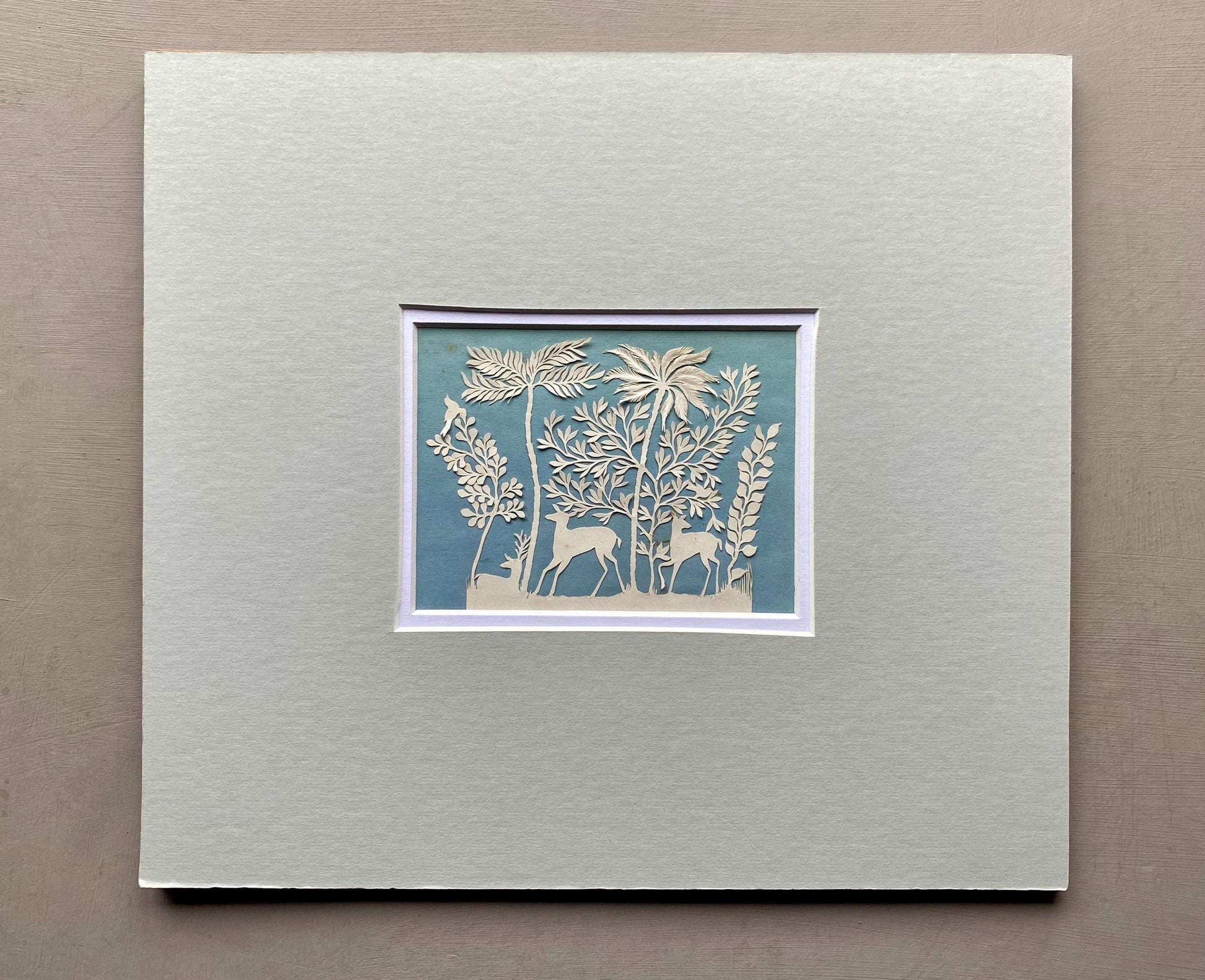 An Antique Paper Cut. Deer In a Wood. White on a Pale Blue Ground. Late Georgian, Early Victorian. Size: 9 x 12.5 cms.