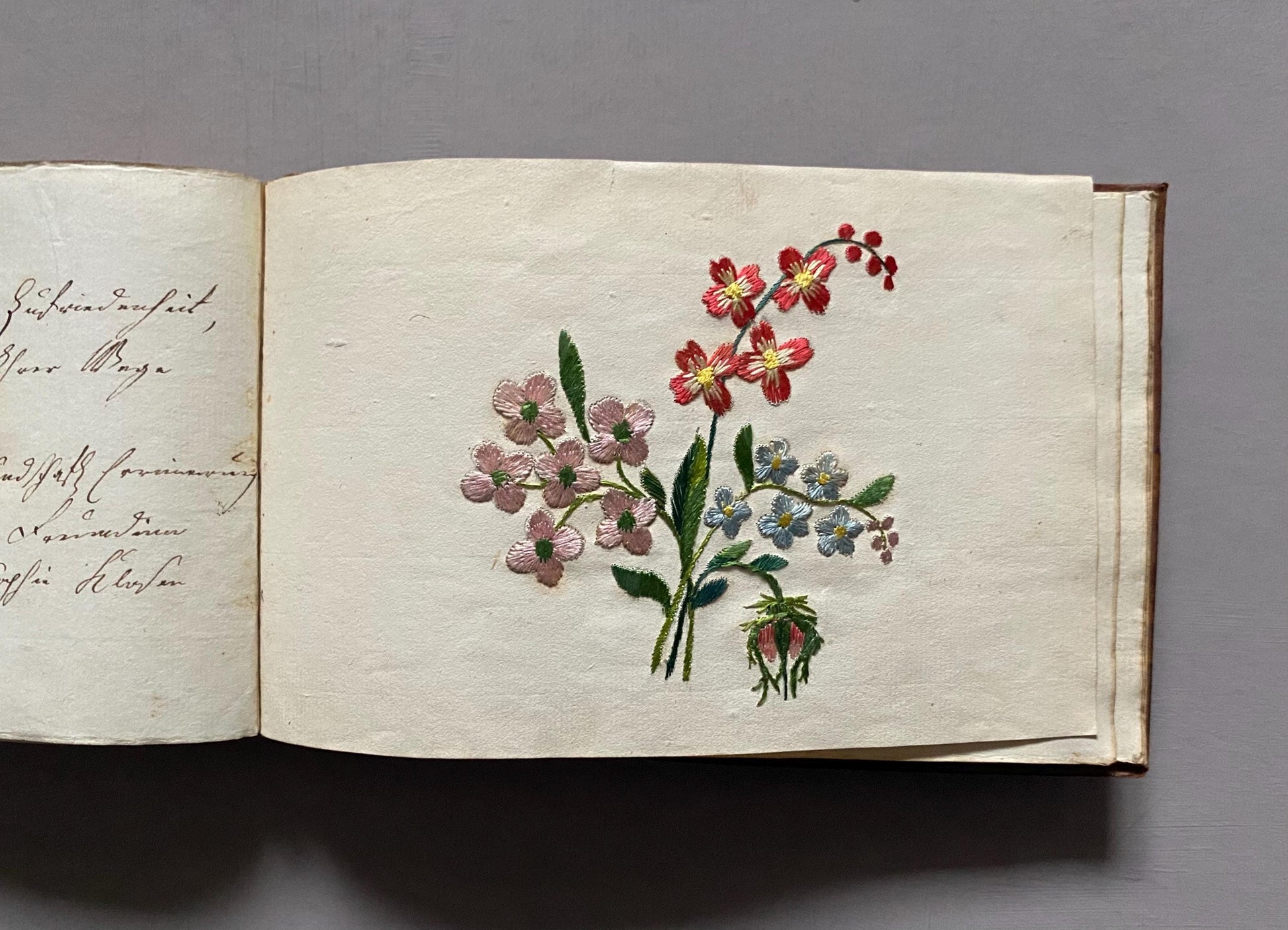A Leatherbound Autograph Book Containing 5 Watercolours and A Needlework Posy. German. Early 1800s. Size: 12 x 18.5 cms.