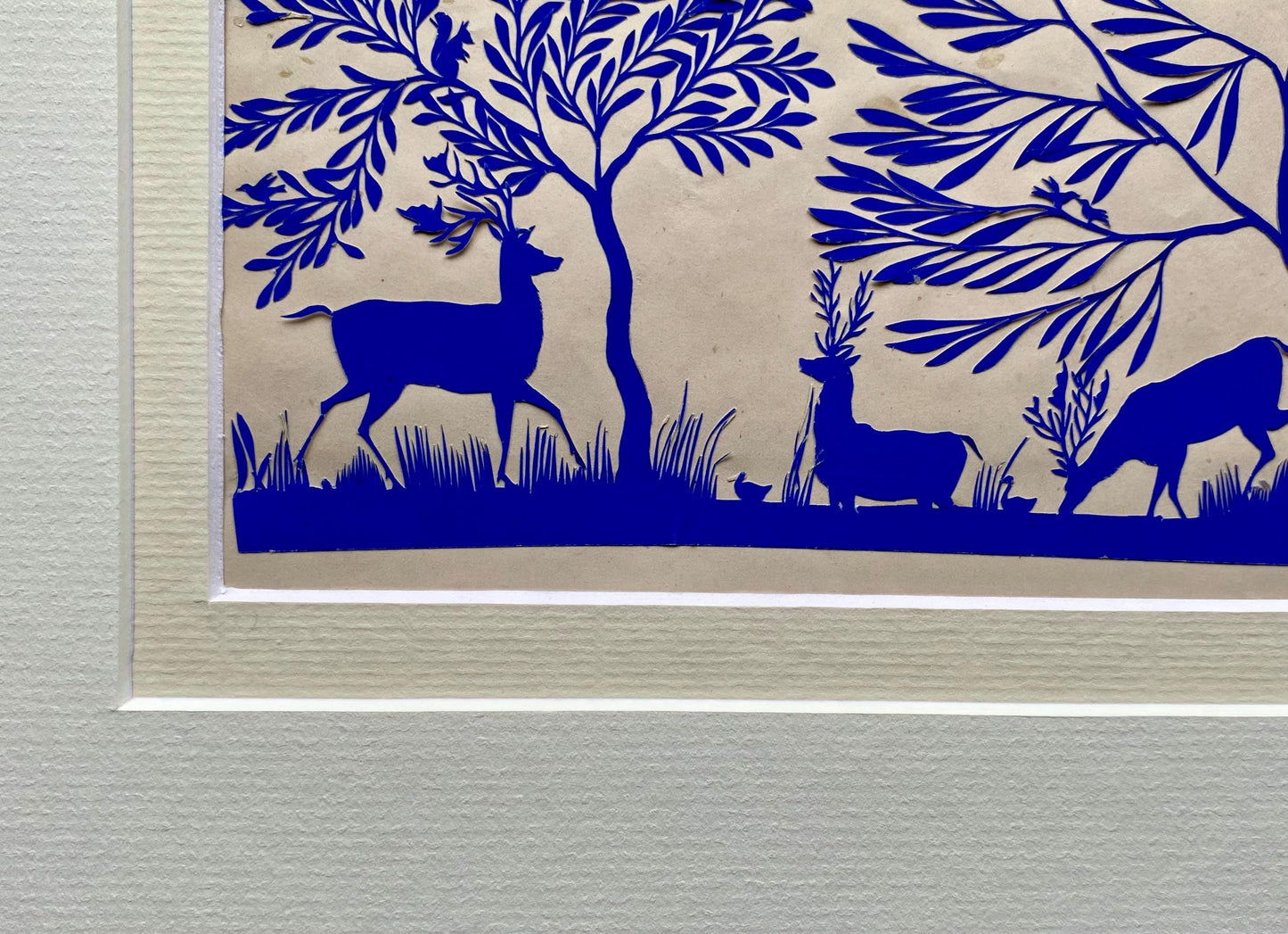 An Antique Paper Cut. Deer At A Pond. Blue on a Pinkish Cream Ground. Late Georgian, Early Victorian. Size: 12.7 x 21.5 cms.