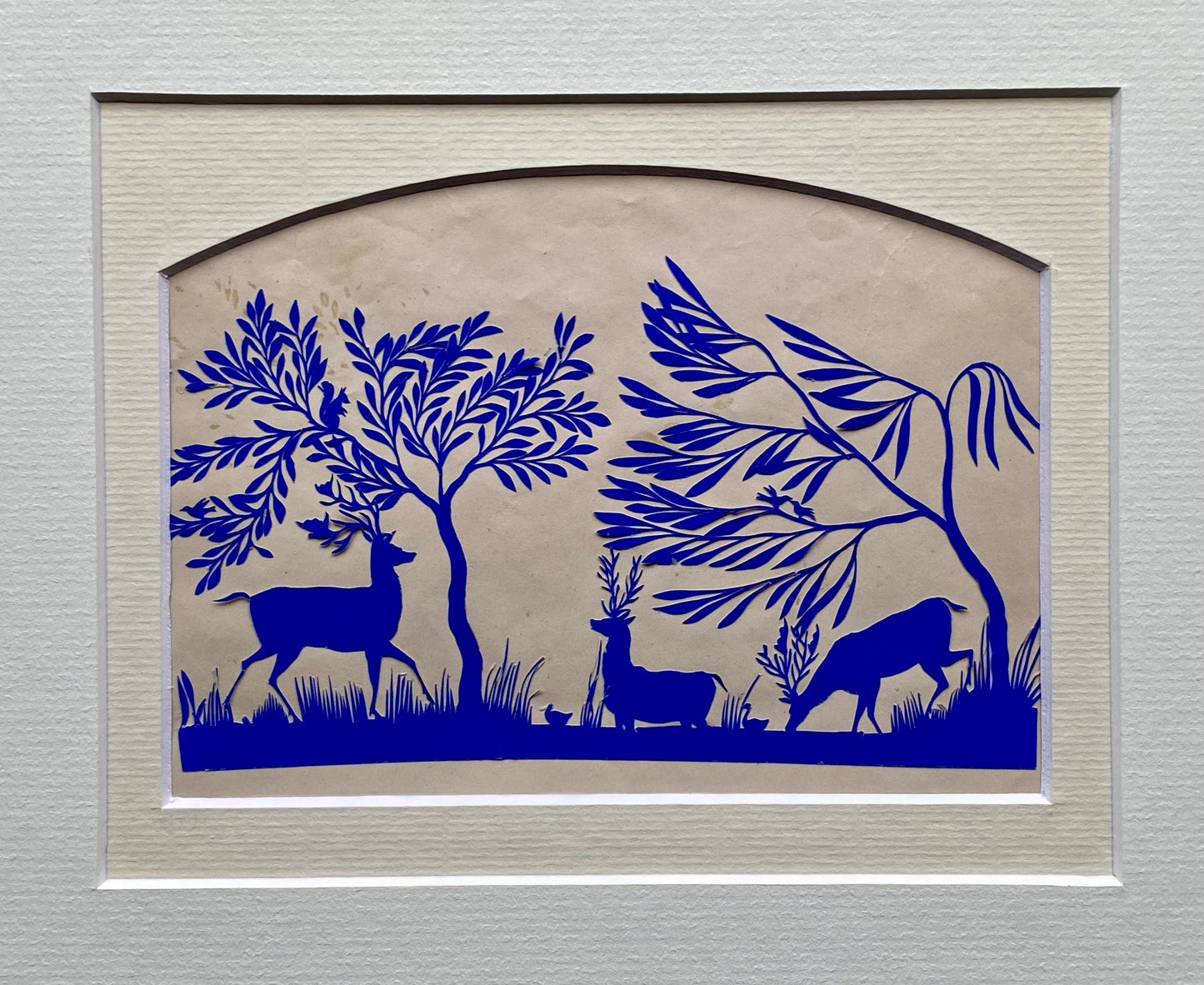 An Antique Paper Cut. Deer At A Pond. Blue on a Pinkish Cream Ground. Late Georgian, Early Victorian. Size: 12.7 x 21.5 cms.