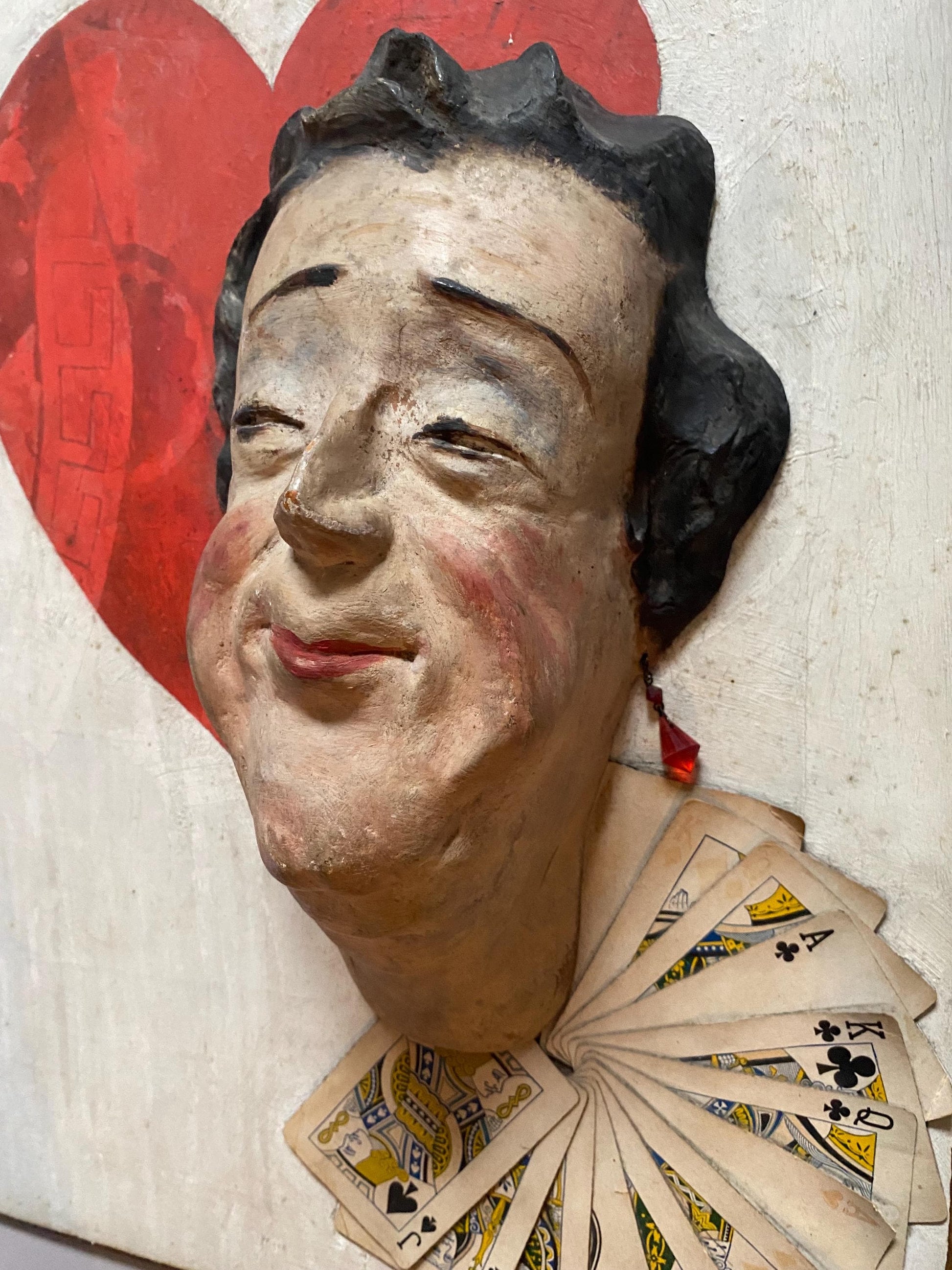 The Queen of Hearts. A Plaster Head Affixed To Decorated Board With Decorative Playing Cards and Glass Earrings. 1930s. Size: 38 x 58.5 cms.