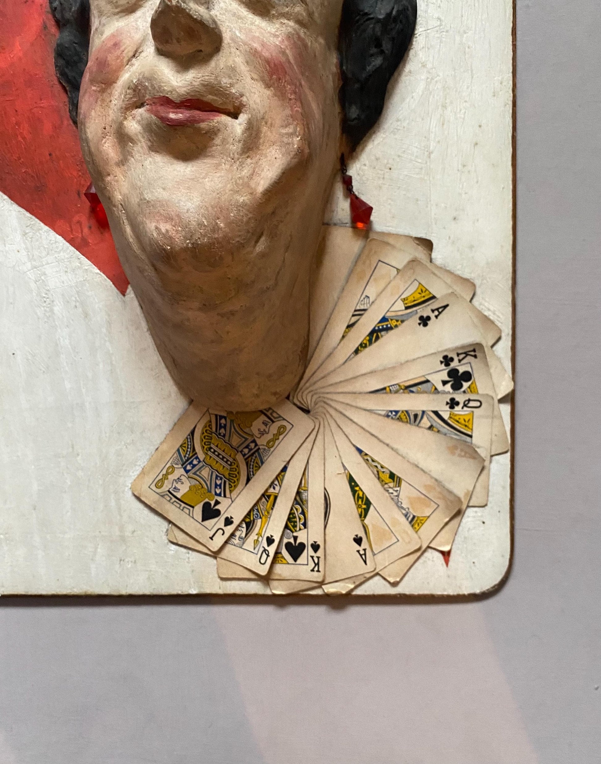 The Queen of Hearts. A Plaster Head Affixed To Decorated Board With Decorative Playing Cards and Glass Earrings. 1930s. Size: 38 x 58.5 cms.