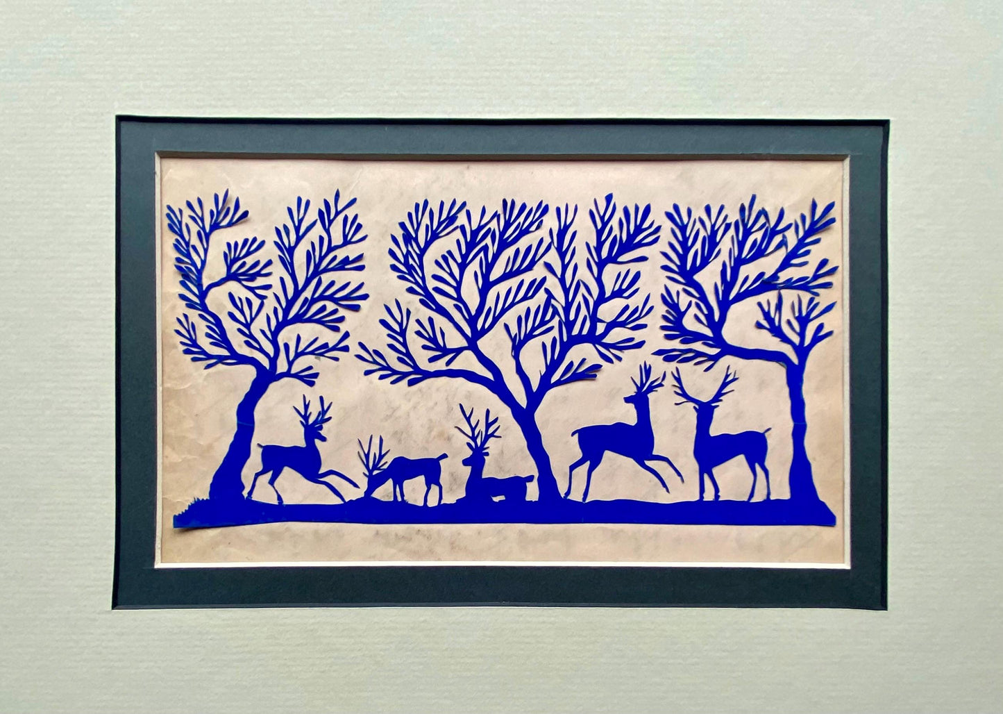 An Antique Paper Cut. Deer In a Wood. Blue on a Pale Pink Ground. Late Georgian, Early Victorian. Size: 12.7 x 21.5 cms.