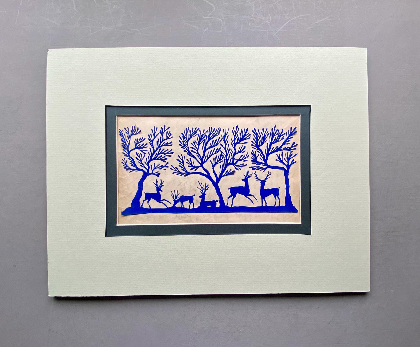 An Antique Paper Cut. Deer In a Wood. Blue on a Pale Pink Ground. Late Georgian, Early Victorian. Size: 12.7 x 21.5 cms.