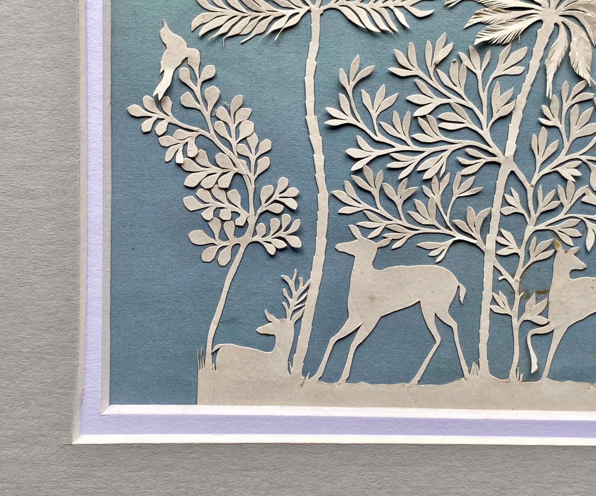 An Antique Paper Cut. Deer In a Wood. White on a Pale Blue Ground. Late Georgian, Early Victorian. Size: 9 x 12.5 cms.