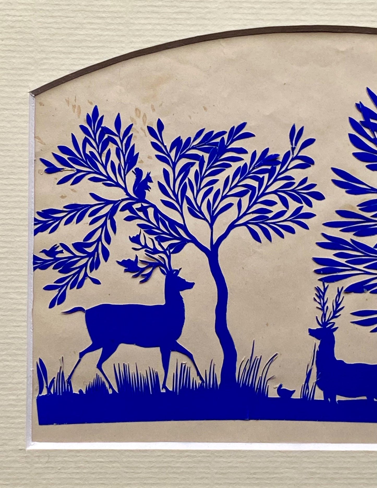 An Antique Paper Cut. Deer At A Pond. Blue on a Pinkish Cream Ground. Late Georgian, Early Victorian. Size: 12.7 x 21.5 cms.