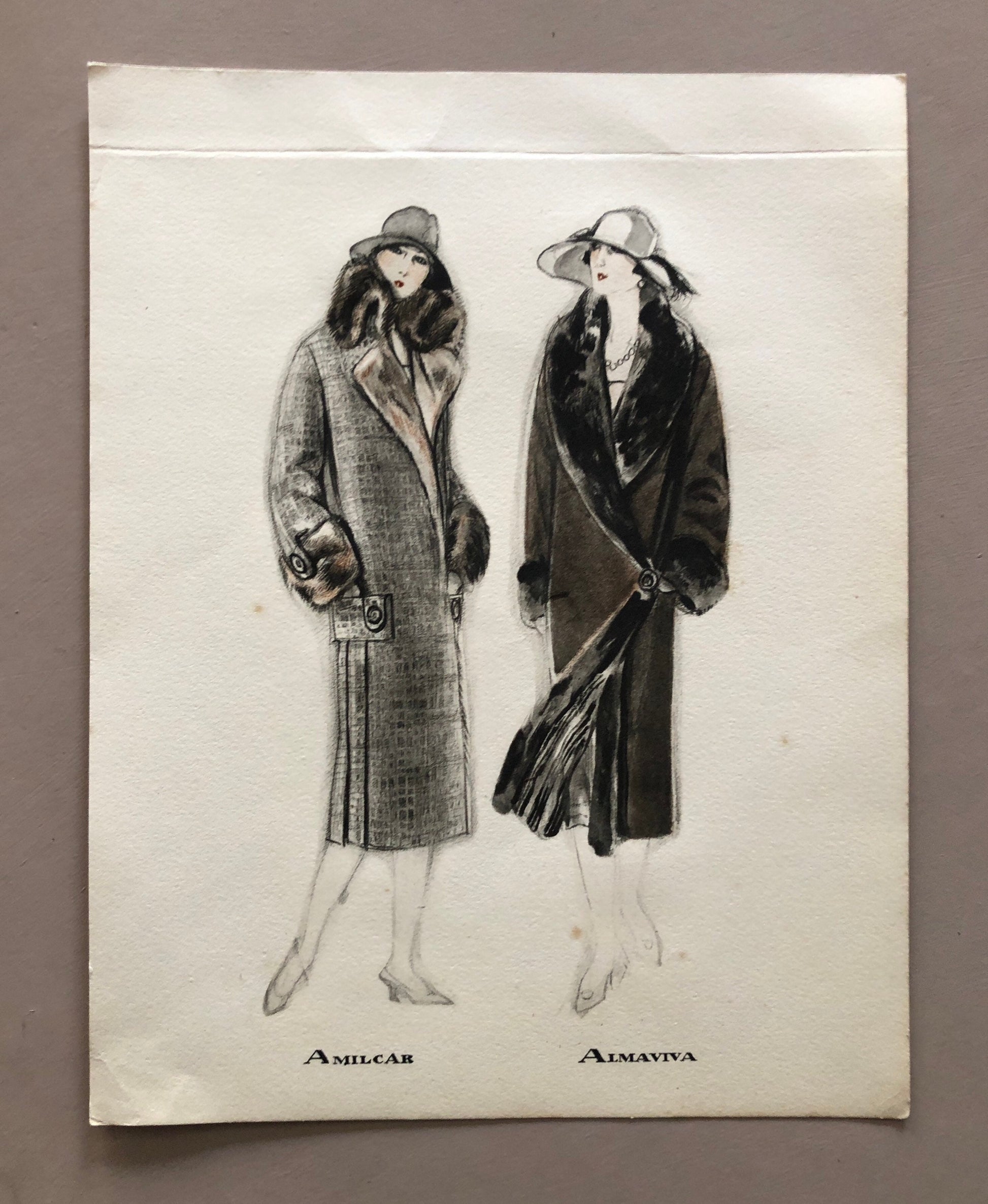 May include: A black and white illustration of two women wearing fur-trimmed coats. The woman on the left is wearing a gray coat with a brown fur collar and cuffs. The woman on the right is wearing a black coat with a black fur collar and cuffs. Both women are wearing hats. The text "Amilcar" and "Almaviva" is printed below the women.